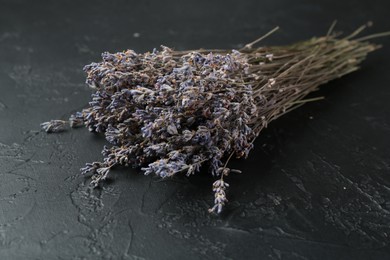 Photo of Bunch of fragrant lavender flowers on black textured table, closeup