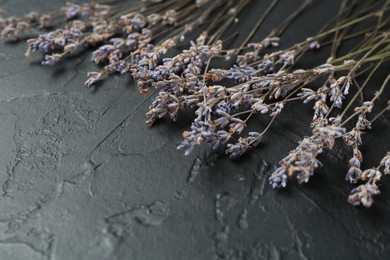 Photo of Fragrant lavender flowers on black textured table, closeup. Space for text