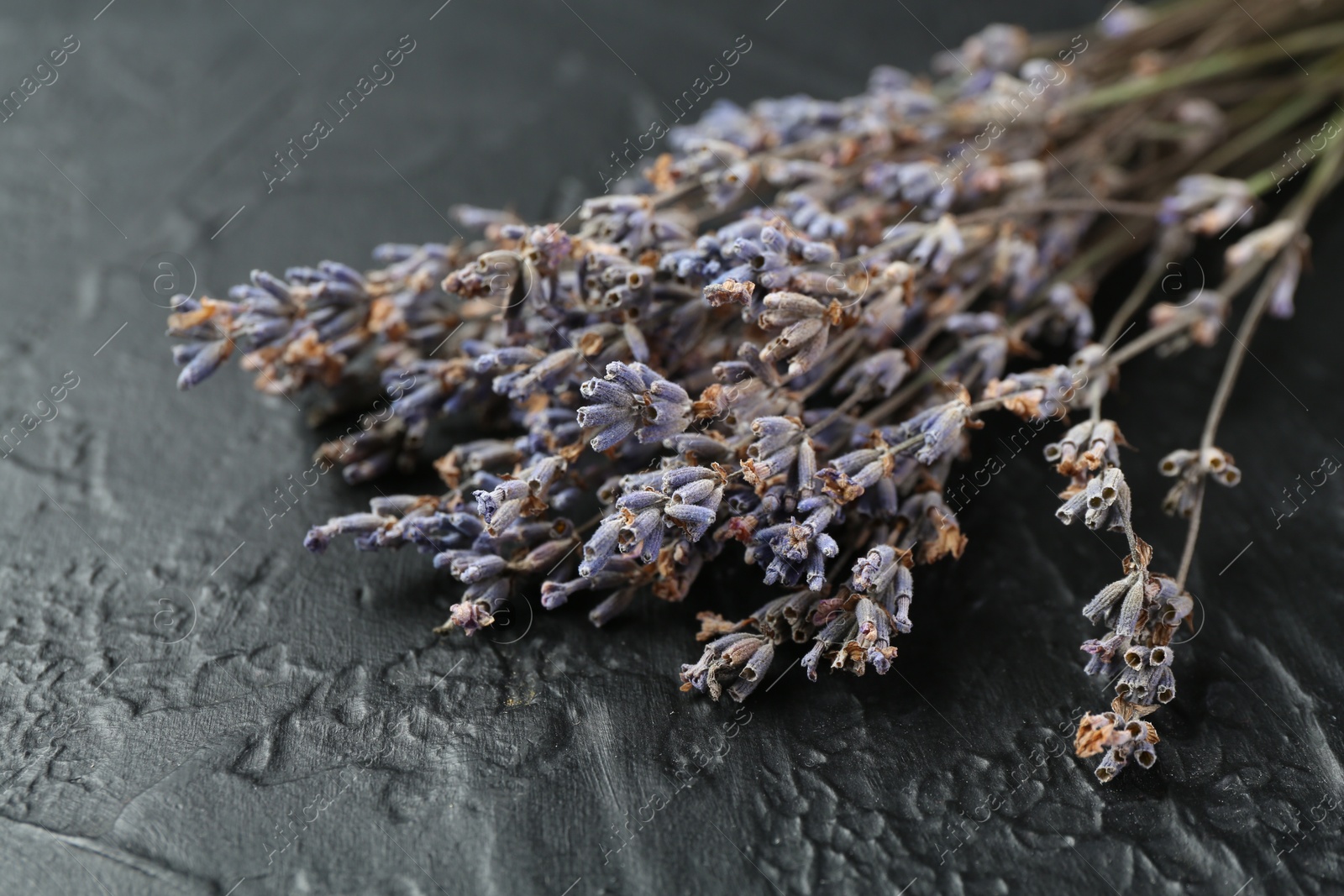 Photo of Fragrant lavender flowers on black textured table, closeup
