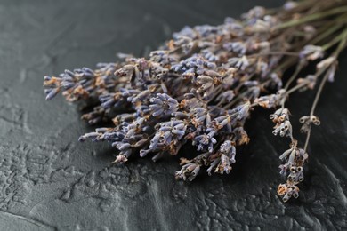 Photo of Fragrant lavender flowers on black textured table, closeup