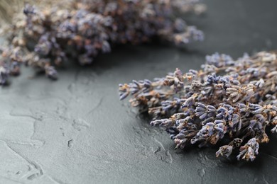 Photo of Fragrant lavender flowers on black textured table, closeup. Space for text