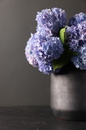 Photo of Beautiful hortensia flowers in vase on black table, closeup