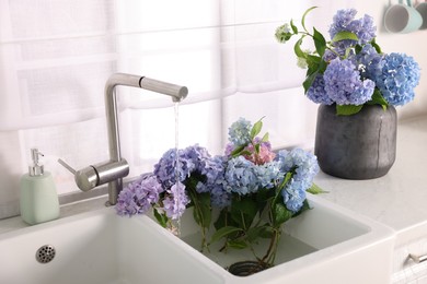 Photo of Bouquets of beautiful blue hortensia flowers in kitchen