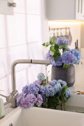 Photo of Bouquets of beautiful blue hortensia flowers in kitchen
