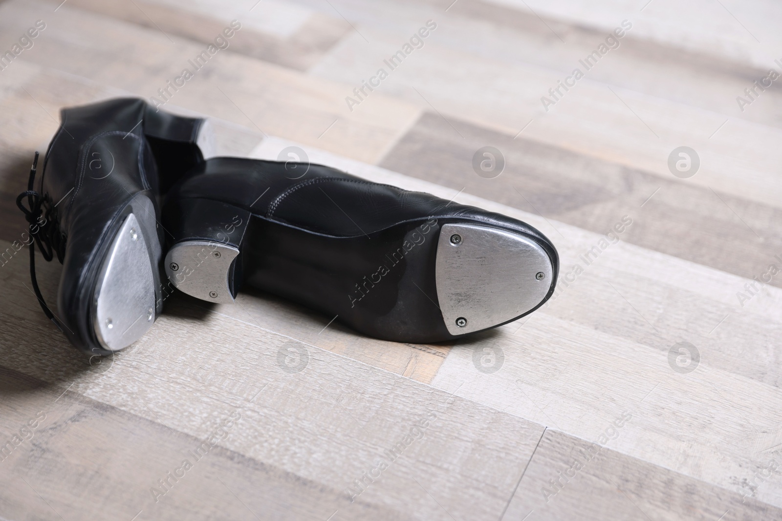 Photo of Pair of shoes for tap dance on floor, closeup. Space for text