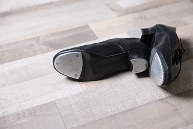 Photo of Pair of shoes for tap dance on floor, closeup. Space for text