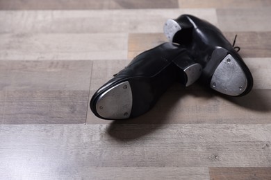 Photo of Pair of shoes for tap dance on floor, closeup. Space for text