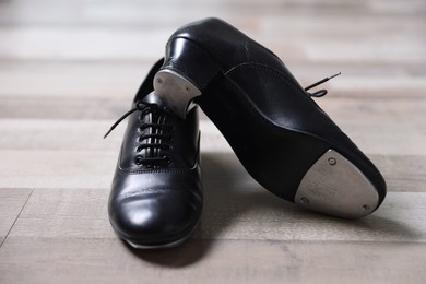 Photo of Pair of shoes for tap dance on floor, closeup