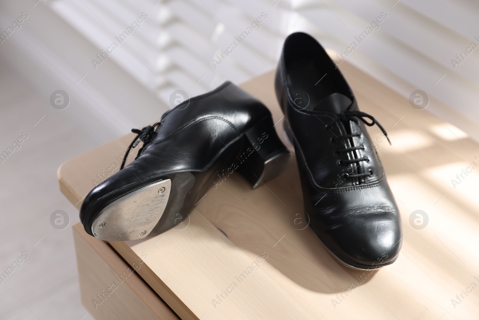 Photo of Pair of shoes for tap dance on wooden cabinet indoors, closeup