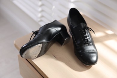 Photo of Pair of shoes for tap dance on wooden cabinet indoors, closeup