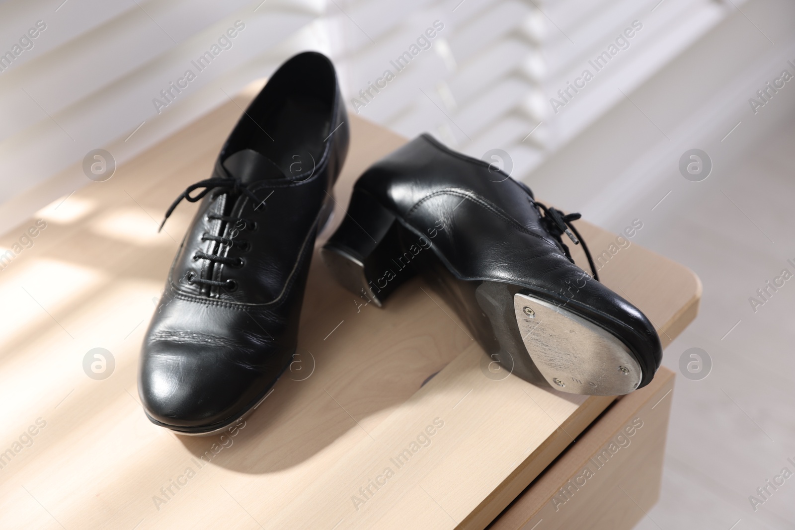 Photo of Pair of shoes for tap dance on wooden cabinet indoors, closeup