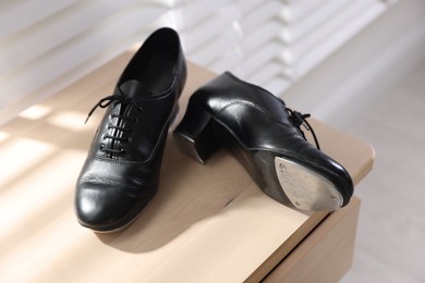 Photo of Pair of shoes for tap dance on wooden cabinet indoors, closeup