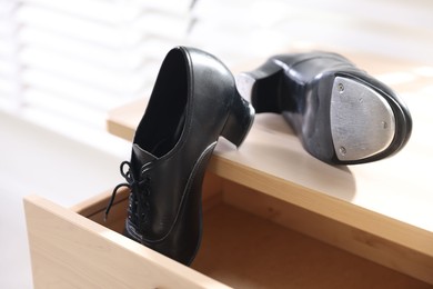 Photo of Pair of shoes for tap dance on wooden cabinet indoors, closeup