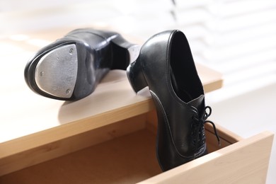 Photo of Pair of shoes for tap dance on wooden cabinet indoors, closeup