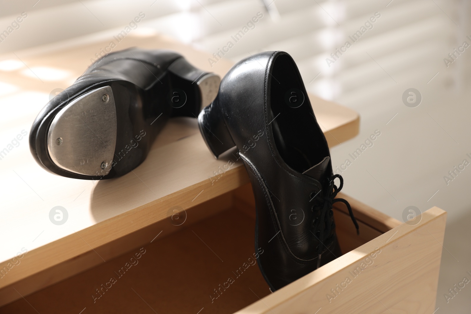 Photo of Pair of shoes for tap dance on wooden cabinet indoors, closeup
