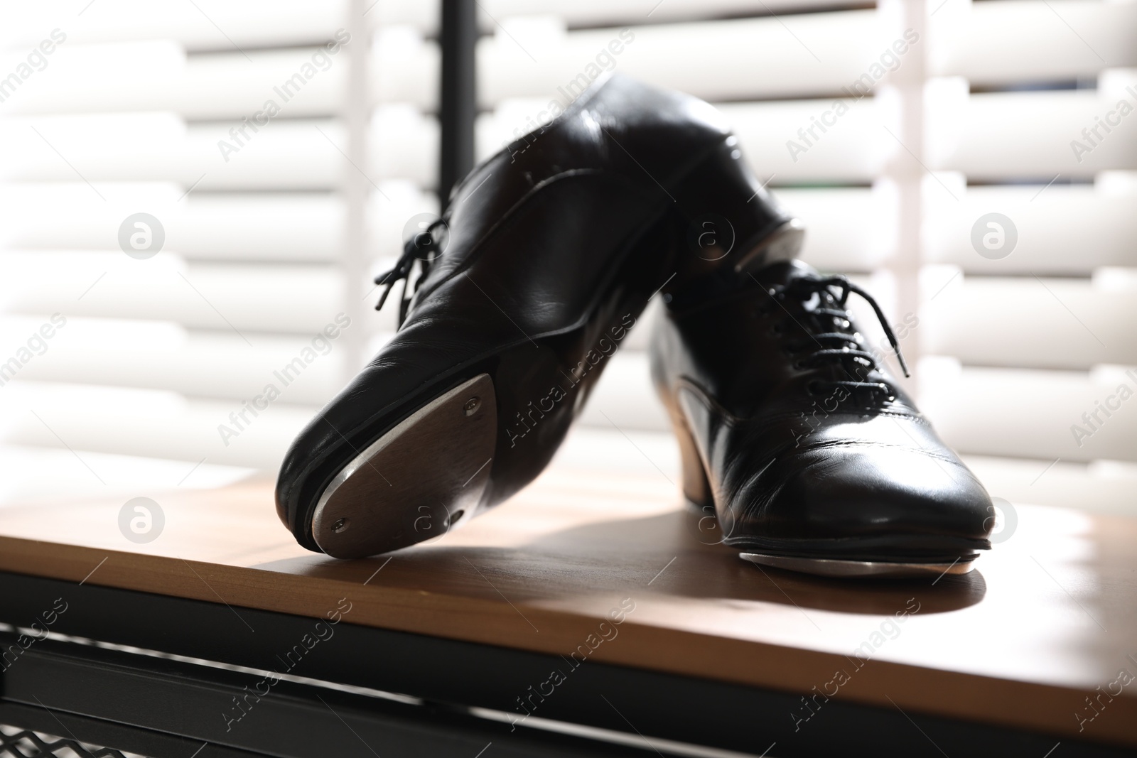 Photo of Pair of shoes for tap dance on wooden shelf indoors, closeup