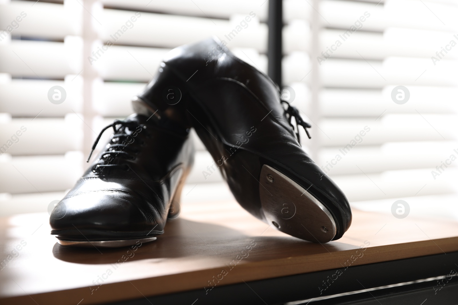 Photo of Pair of shoes for tap dance on wooden shelf indoors, closeup