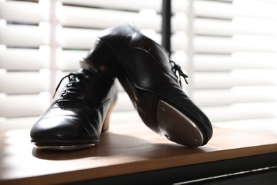 Photo of Pair of shoes for tap dance on wooden shelf indoors, closeup