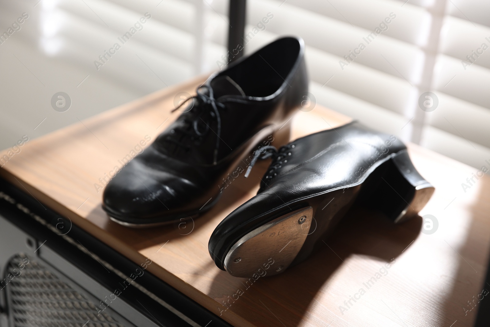 Photo of Pair of shoes for tap dance on wooden shelf indoors, closeup
