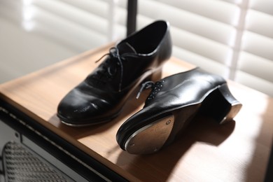 Photo of Pair of shoes for tap dance on wooden shelf indoors, closeup