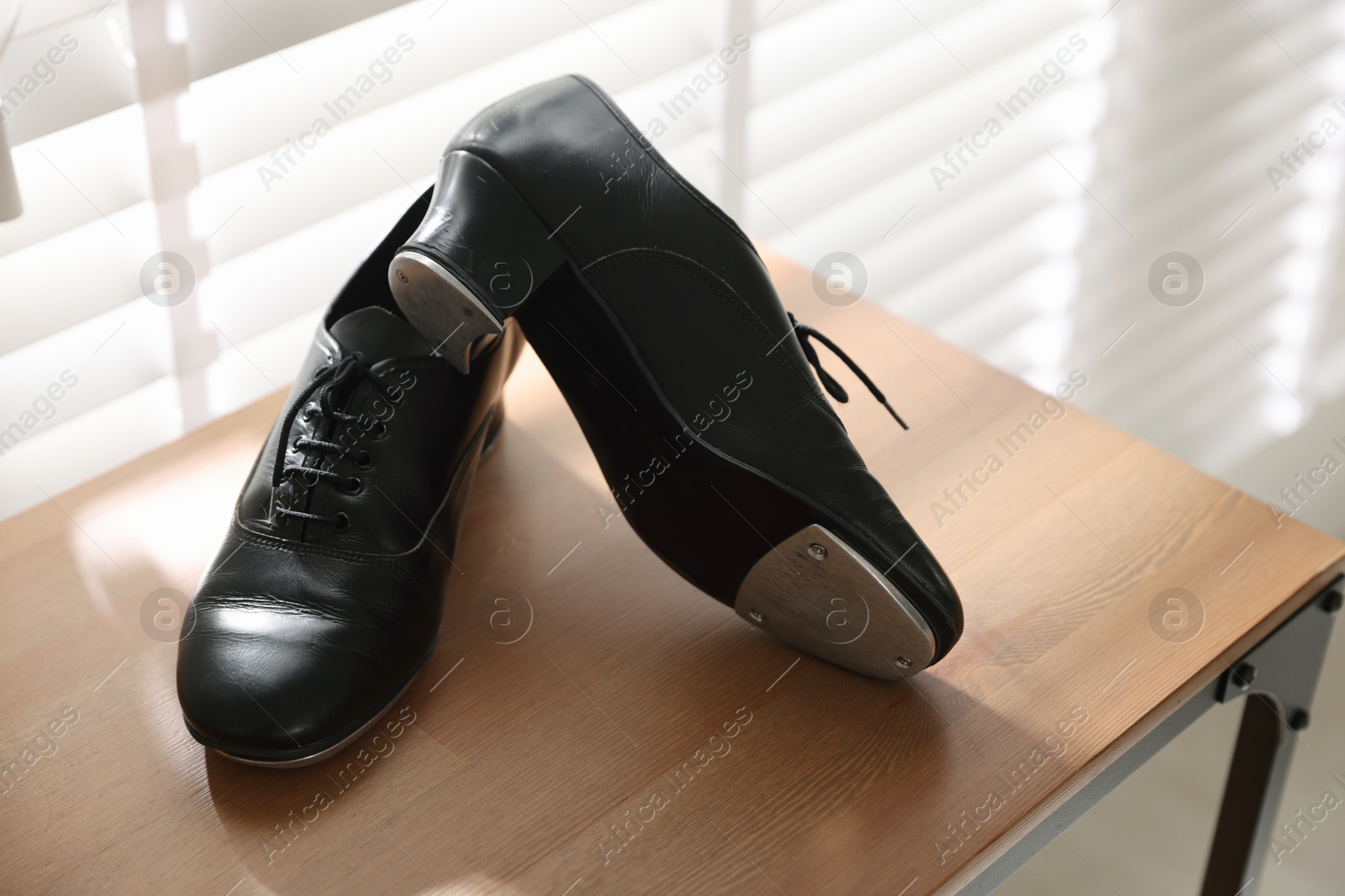 Photo of Pair of shoes for tap dance on wooden shelf indoors, closeup