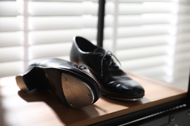 Photo of Pair of shoes for tap dance on wooden shelf indoors, closeup