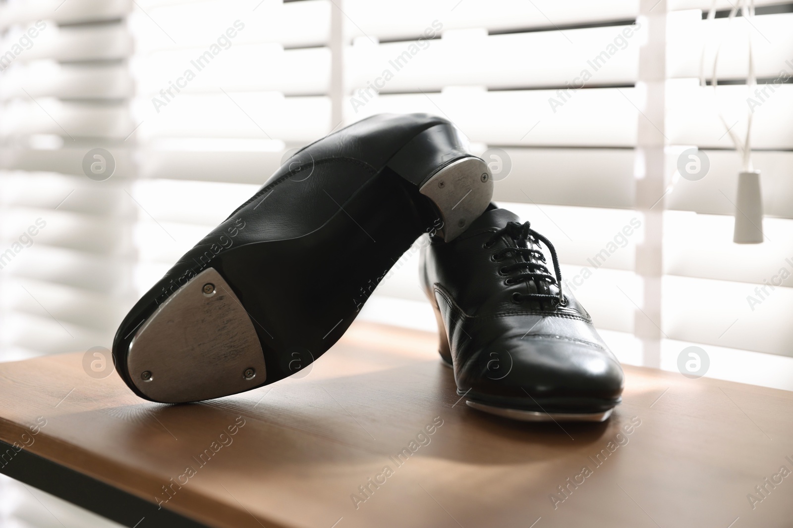 Photo of Pair of shoes for tap dance on wooden shelf indoors, closeup