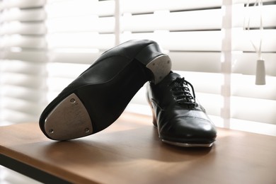 Photo of Pair of shoes for tap dance on wooden shelf indoors, closeup