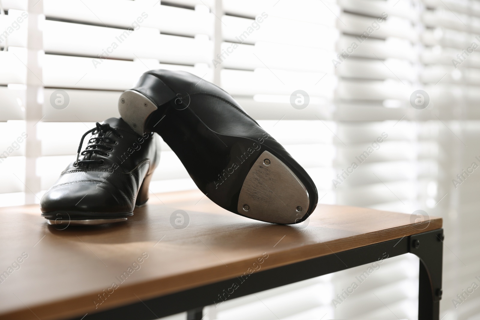Photo of Pair of shoes for tap dance on wooden shelf indoors, closeup