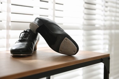 Photo of Pair of shoes for tap dance on wooden shelf indoors, closeup