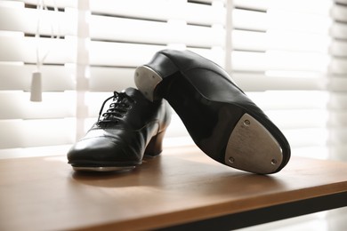 Photo of Pair of shoes for tap dance on wooden shelf indoors, closeup