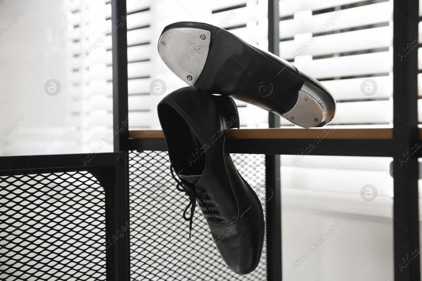 Photo of Pair of shoes for tap dance on wooden shelf indoors