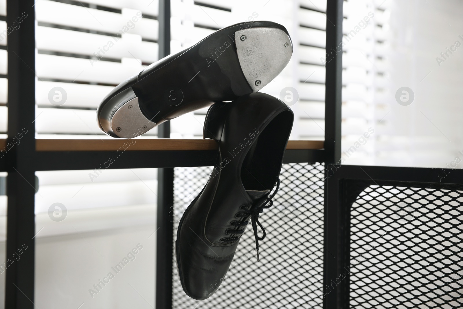 Photo of Pair of shoes for tap dance on wooden shelf indoors