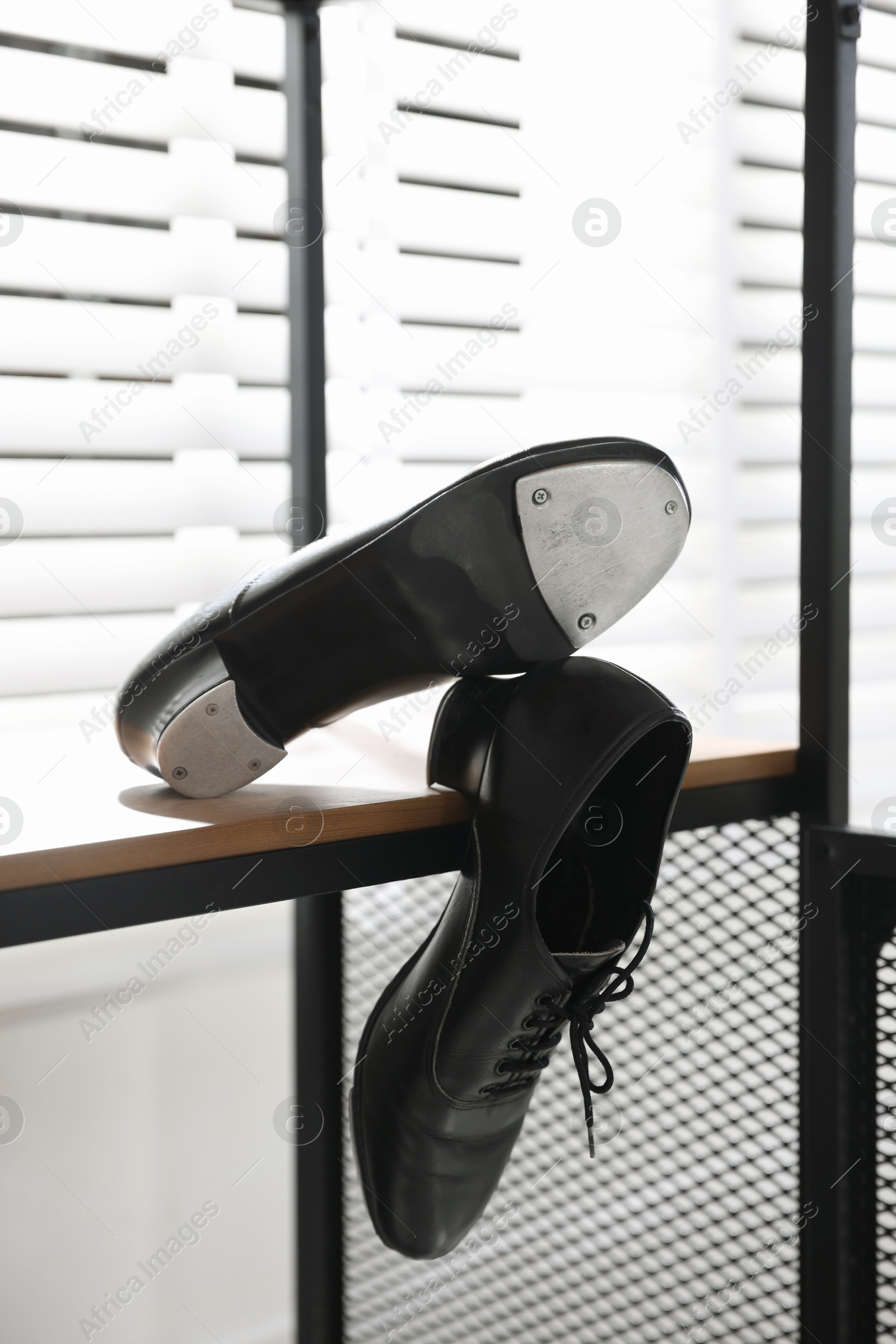 Photo of Pair of shoes for tap dance on wooden shelf indoors