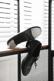Photo of Pair of shoes for tap dance on wooden shelf indoors