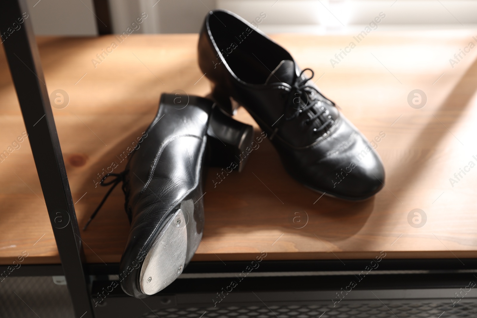 Photo of Pair of shoes for tap dance on wooden shelf indoors, closeup
