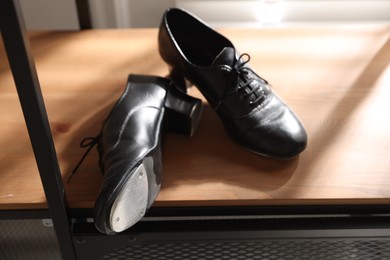 Photo of Pair of shoes for tap dance on wooden shelf indoors, closeup