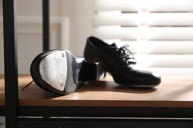 Photo of Pair of shoes for tap dance on cabinet indoors, closeup