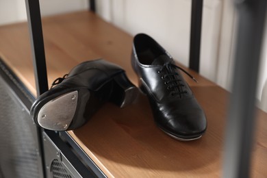 Photo of Pair of shoes for tap dance on cabinet indoors, closeup