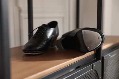 Photo of Pair of shoes for tap dance on cabinet indoors, closeup