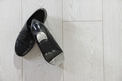Photo of Pair of shoes for tap dance on floor, top view. Space for text