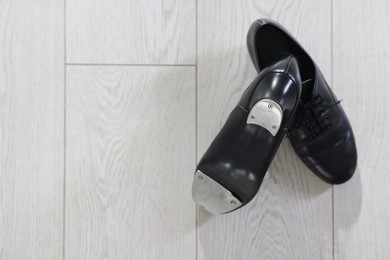 Photo of Pair of shoes for tap dance on floor, top view. Space for text