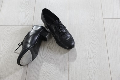 Photo of Pair of shoes for tap dance on floor, above view. Space for text