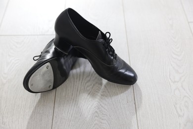 Photo of Pair of shoes for tap dance on floor indoors, closeup