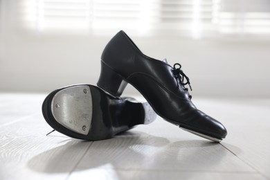 Photo of Pair of shoes for tap dance on floor indoors, closeup