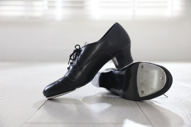 Photo of Pair of shoes for tap dance on floor indoors, closeup