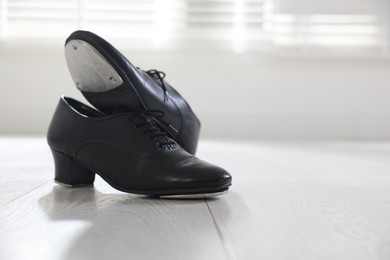 Photo of Pair of shoes for tap dance on floor indoors, closeup. Space for text