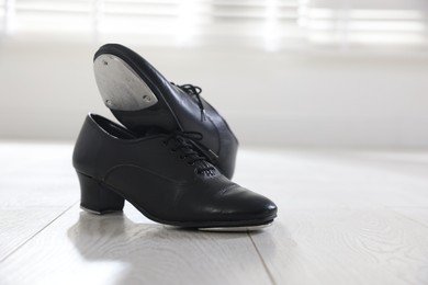 Photo of Pair of shoes for tap dance on floor indoors, closeup. Space for text