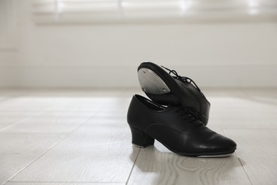 Photo of Pair of shoes for tap dance on floor indoors, space for text