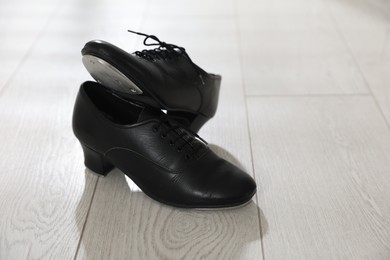Photo of Pair of shoes for tap dance on floor indoors, closeup. Space for text